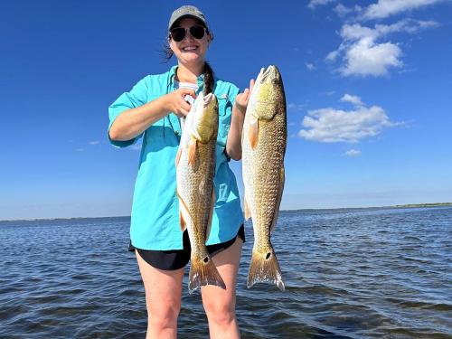 Smiling angler holding two redfish