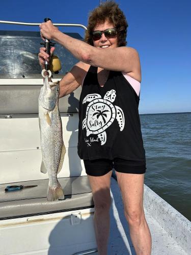 Angler weighing a speckled trout aboard Capt. Dave’s boat