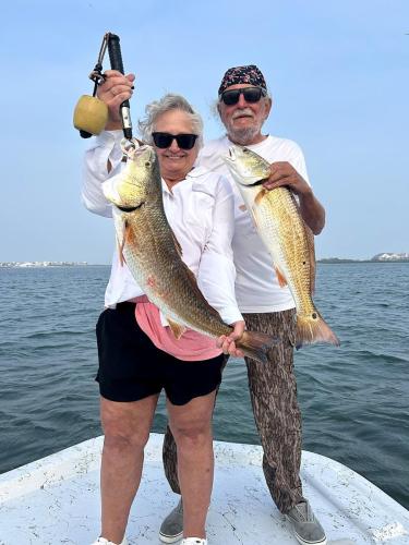 Couple holding two redfish on Capt. Dave Edwards’ boat