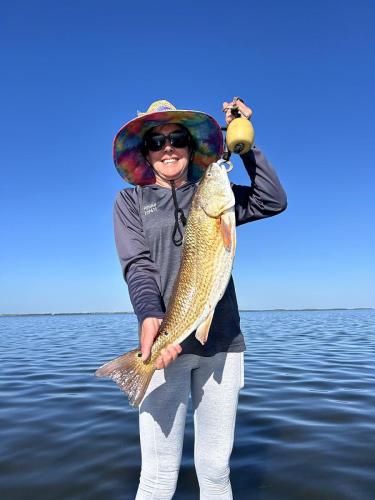Angler in a sun hat holding a redfish