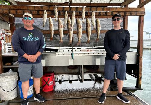 Two anglers with a full rack of redfish and trout